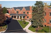 Brick senior living building with driveway, walkway, and trees at entrance.