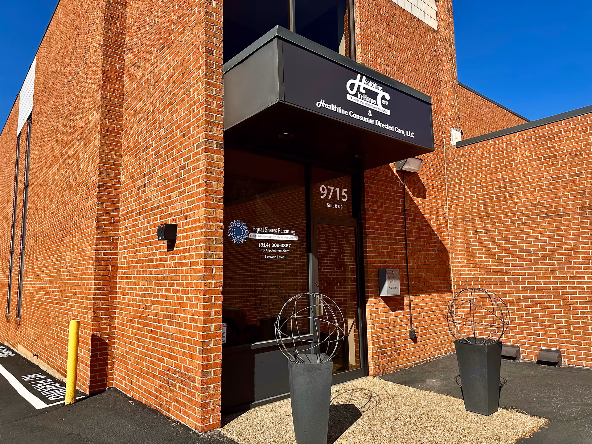 Brick exterior of Healthline In-Home Care building with glass entrance and decorative planters.
