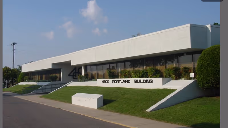 White, modern building facade with large windows and sloped entryways.