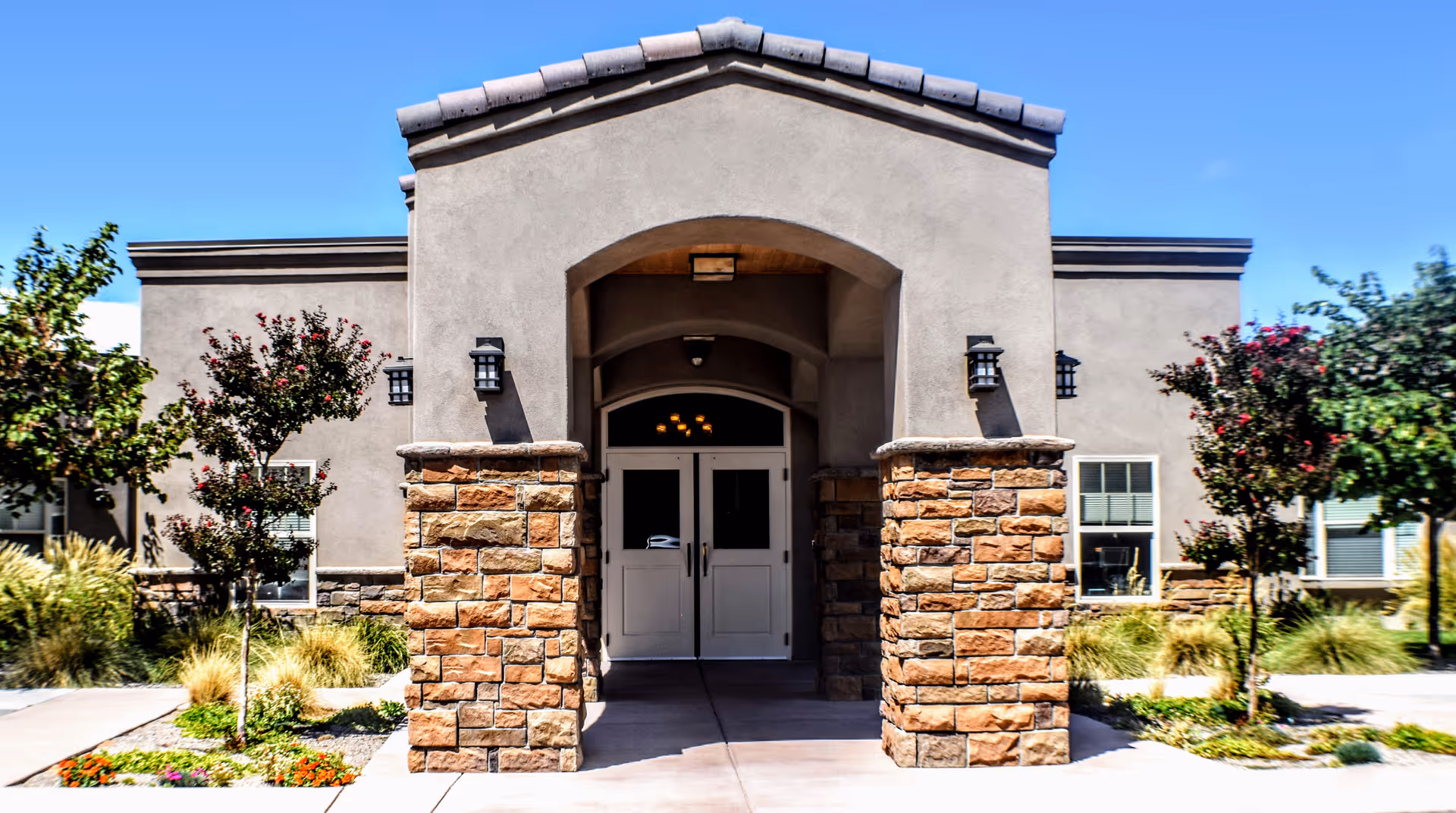 Front entrance of a senior living facility with stone columns and arches.