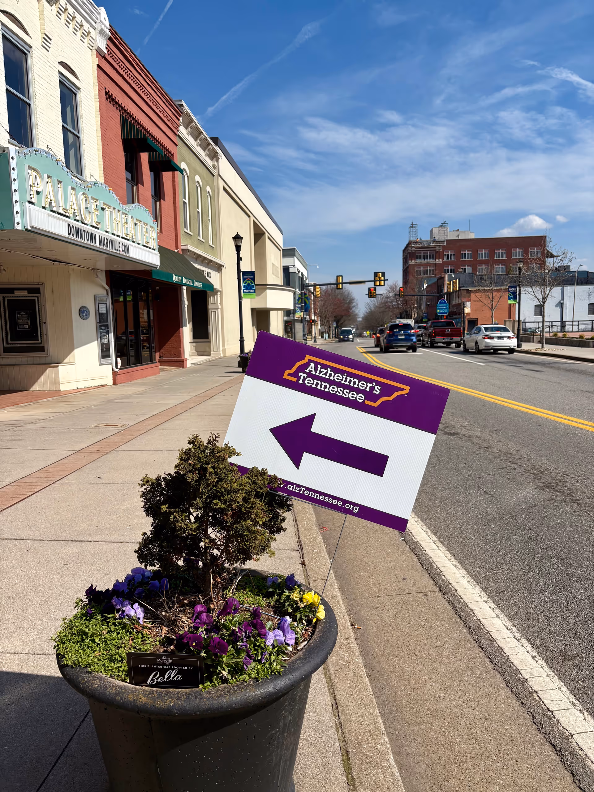 Downtown Knoxville street with a planter, flowers, and an Alzheimer's Tennessee sign.