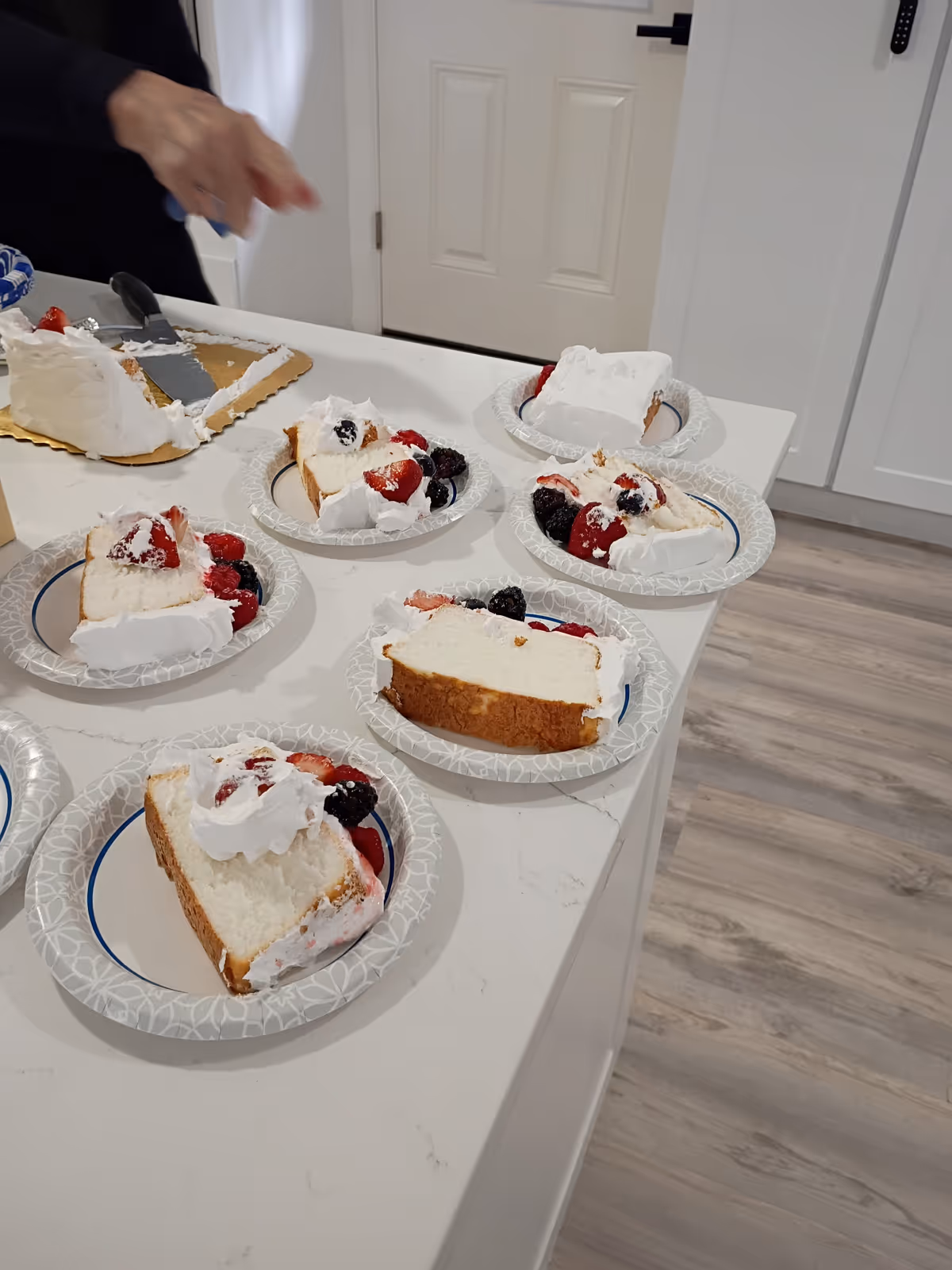 Assorted berry-topped cake slices arranged on a white kitchen counter