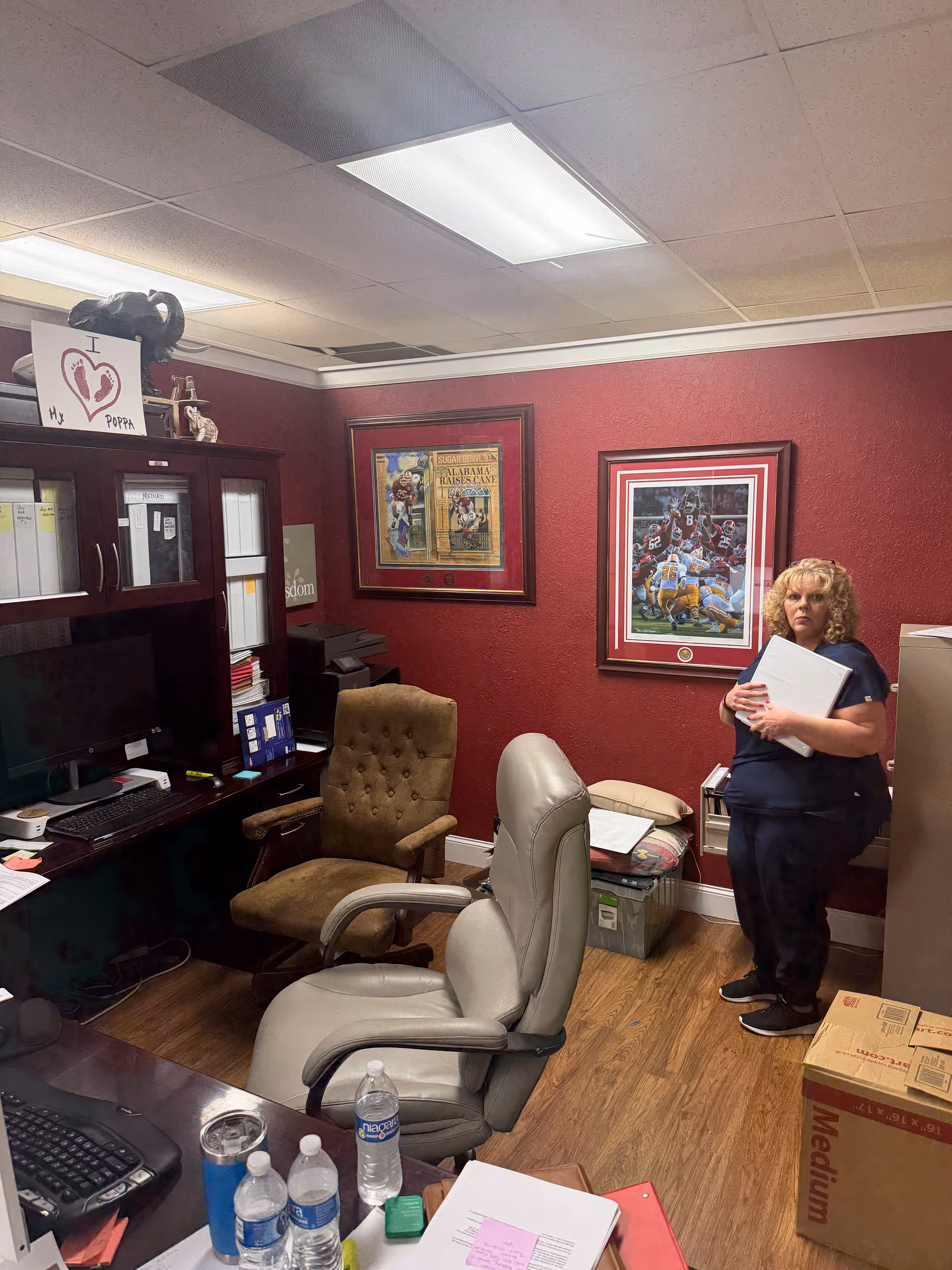 Office workspace inside a senior care facility, with red walls, desks, and a staff member.