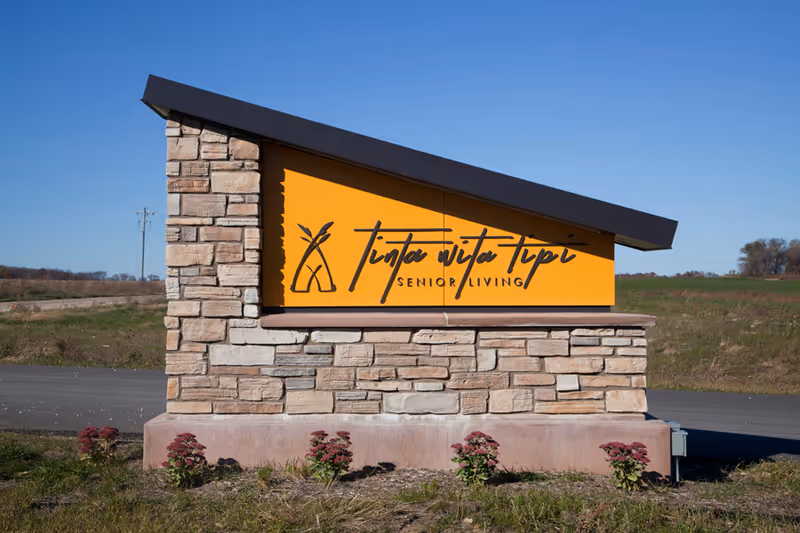 Outdoor stone sign for Tinta Wita Tipi Senior Living along a rural road