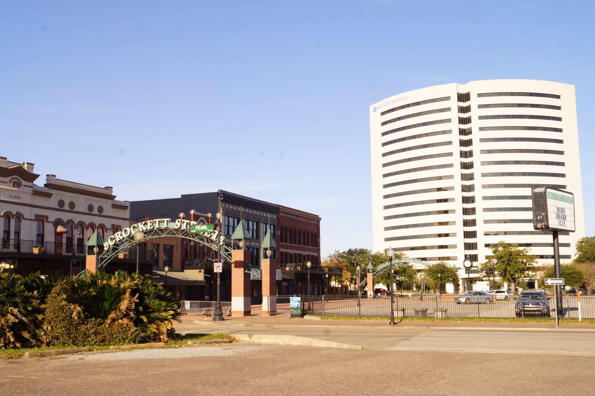 Urban street scene with a curved white office tower and historic storefronts.