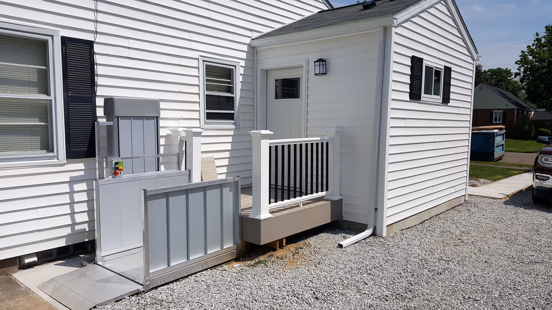 Exterior of a white building with a small ramp and a railing to the door.