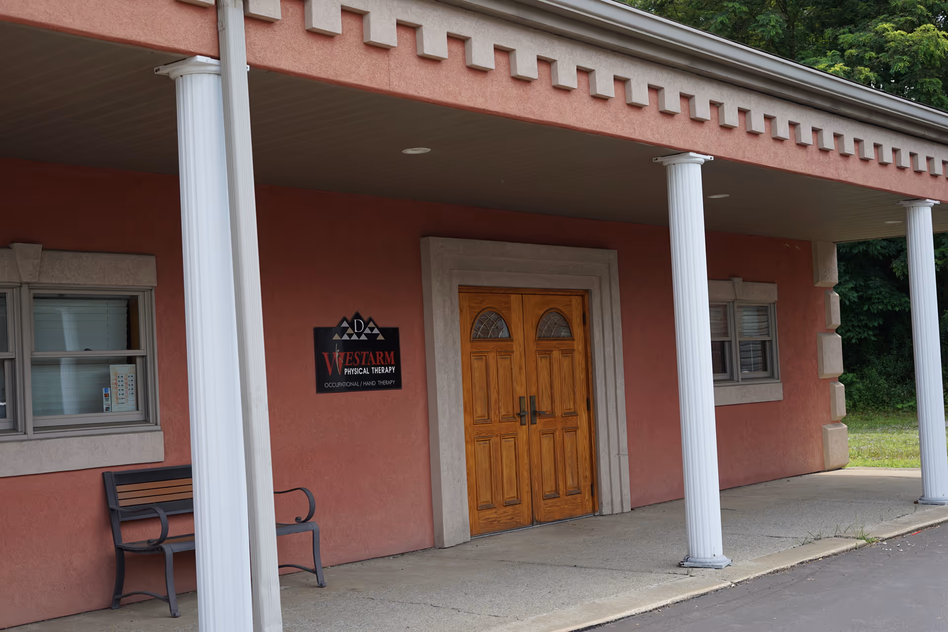 Front view of a pink building entrance with wooden double doors and white columns.