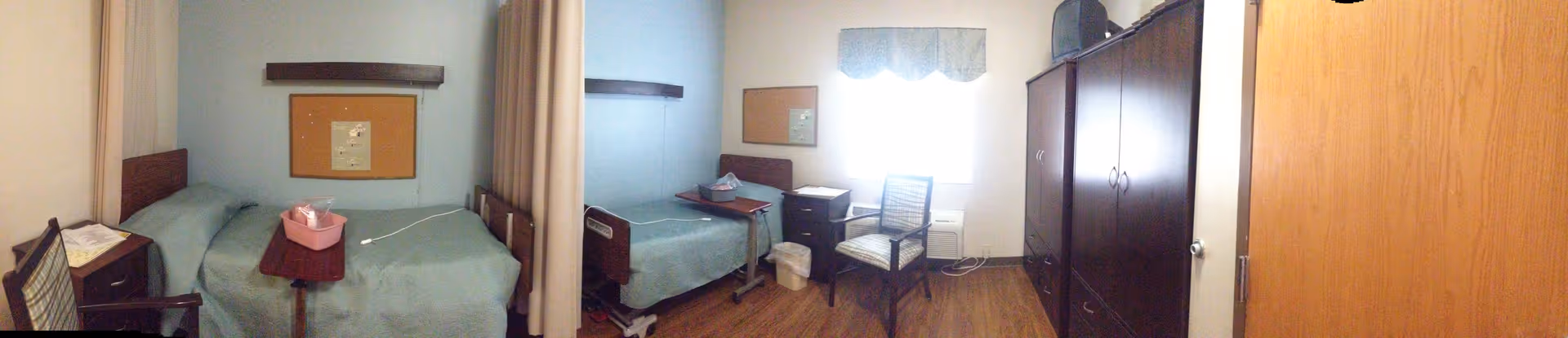 Blue-walled resident room with two beds, a desk, and a wardrobe.