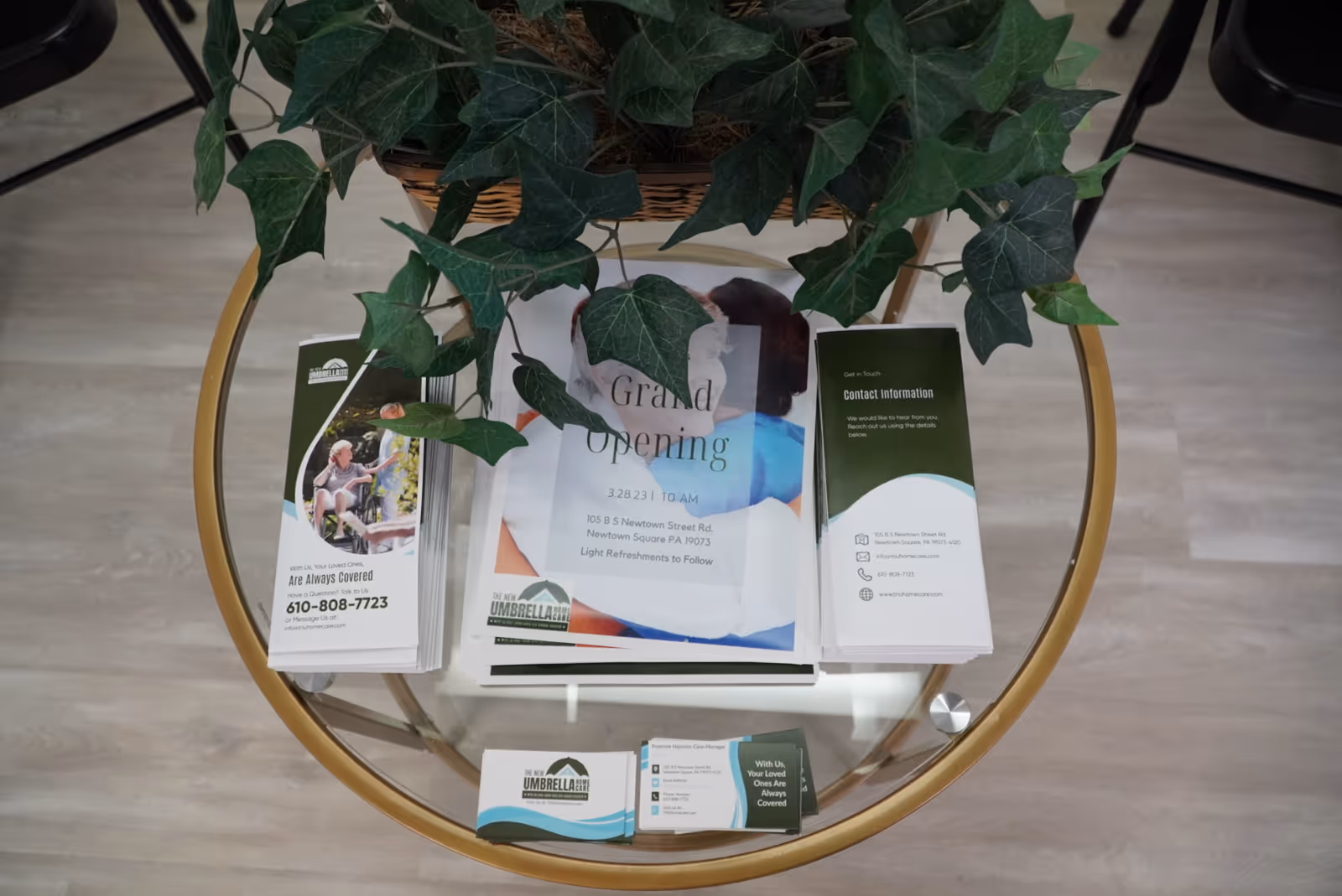 Round glass coffee table with brochures and a plant in a lobby.