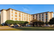 A large multi-story senior living facility with cars parked along a tree-lined front.