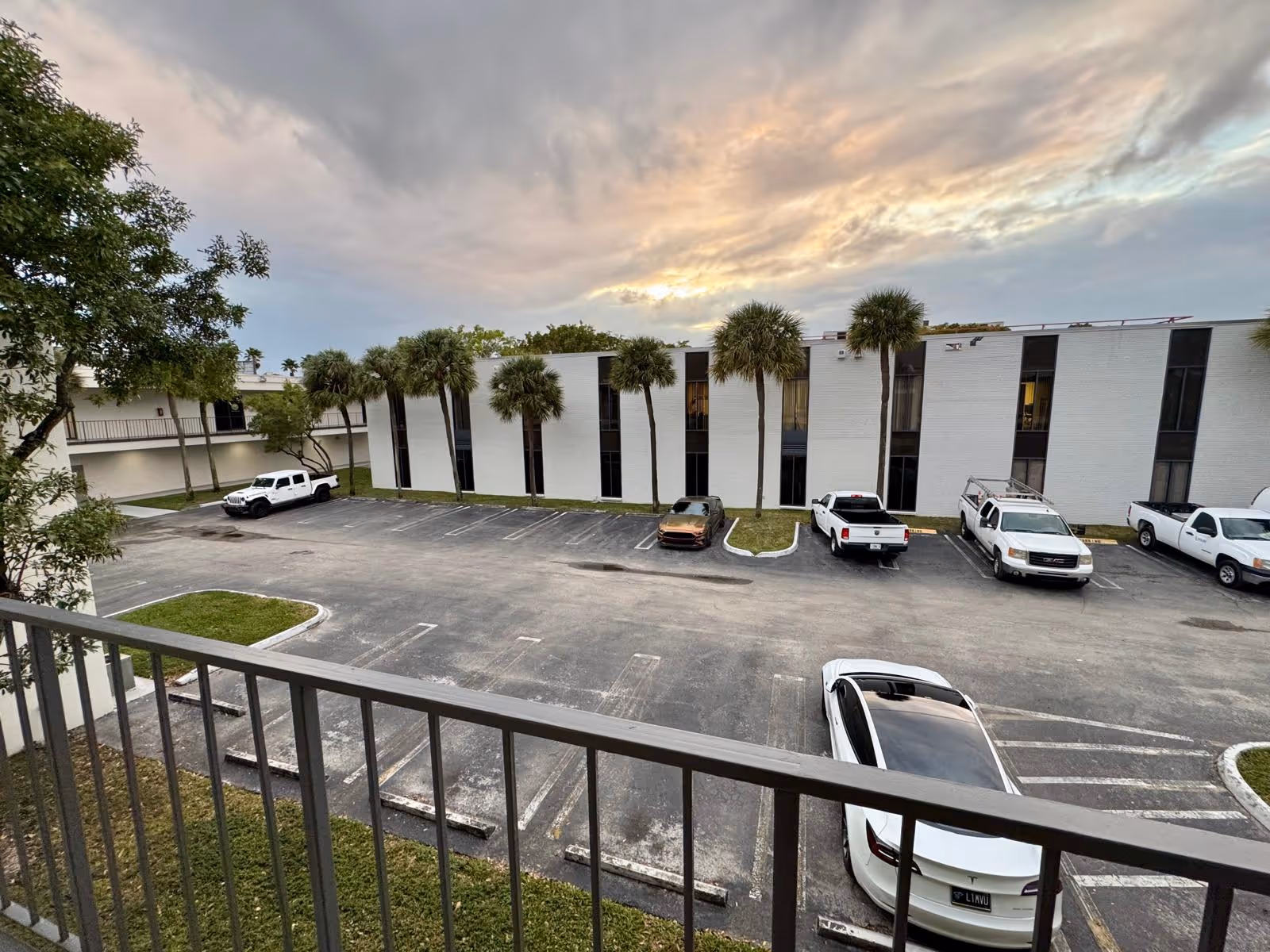 Balcony view of a senior living facility with parked cars and palm trees.