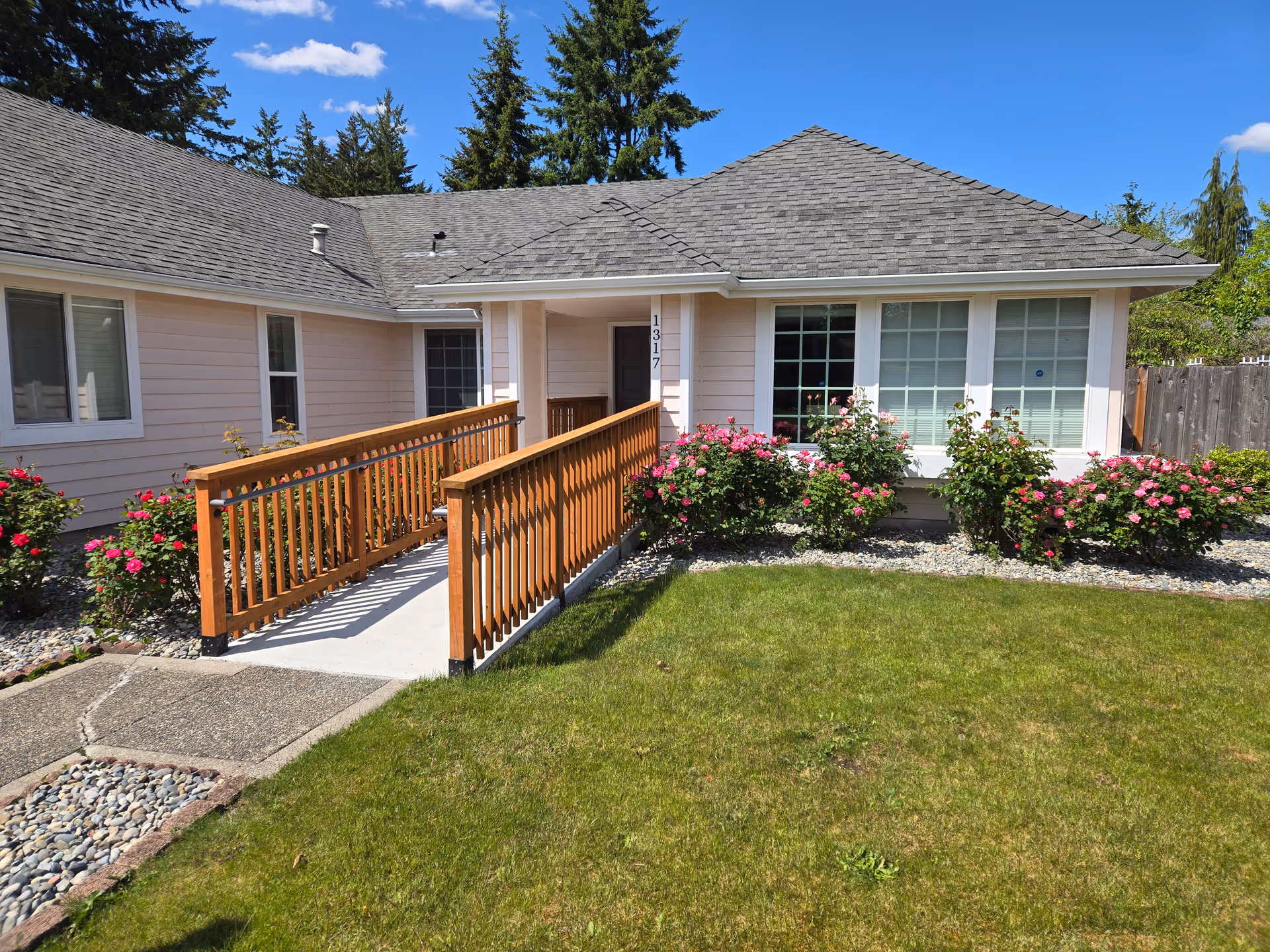 Front exterior of Advent Senior Care Home with ramp, windows, and blooming rose bushes.