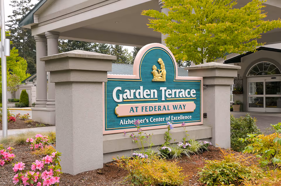 Stone entrance sign for Garden Terrace at Federal Way with landscaping and the facility entrance in the background.