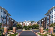 Wide view of Evergreens at Columbia Town Center exterior, a U-shaped brick residential building with landscaping.