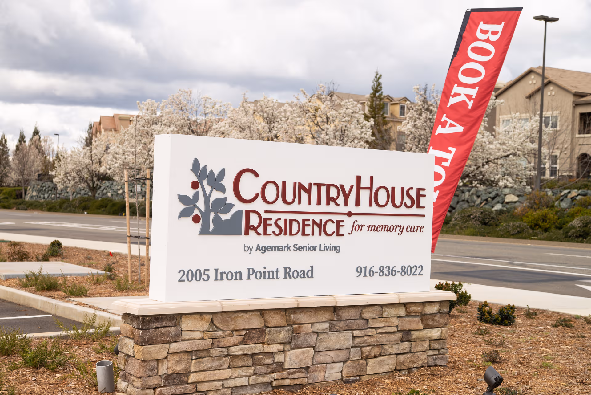 Outdoor sign for CountryHouse Residence with stone base and red flag