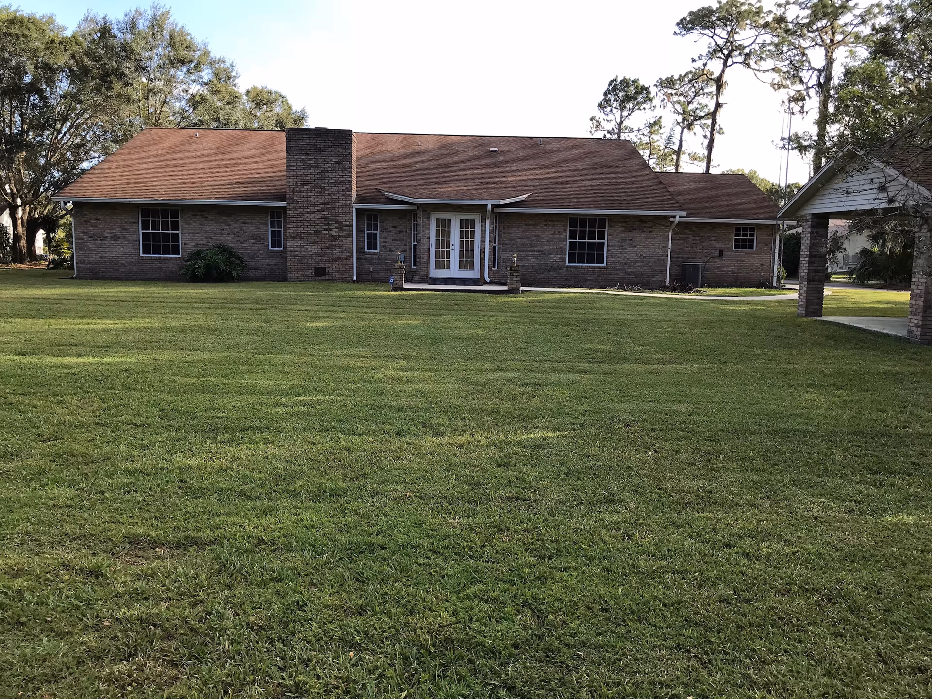 Single-story brick senior living facility with front entrance, chimney, and expansive green lawn.