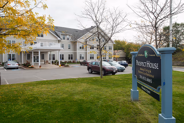 Front view of Prospect House assisted living building with parking lot and sign.