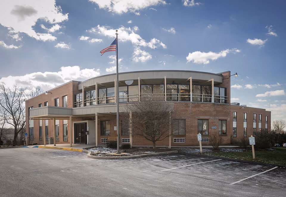 Exterior of Towne Manor East senior living facility with flagpole and parking.