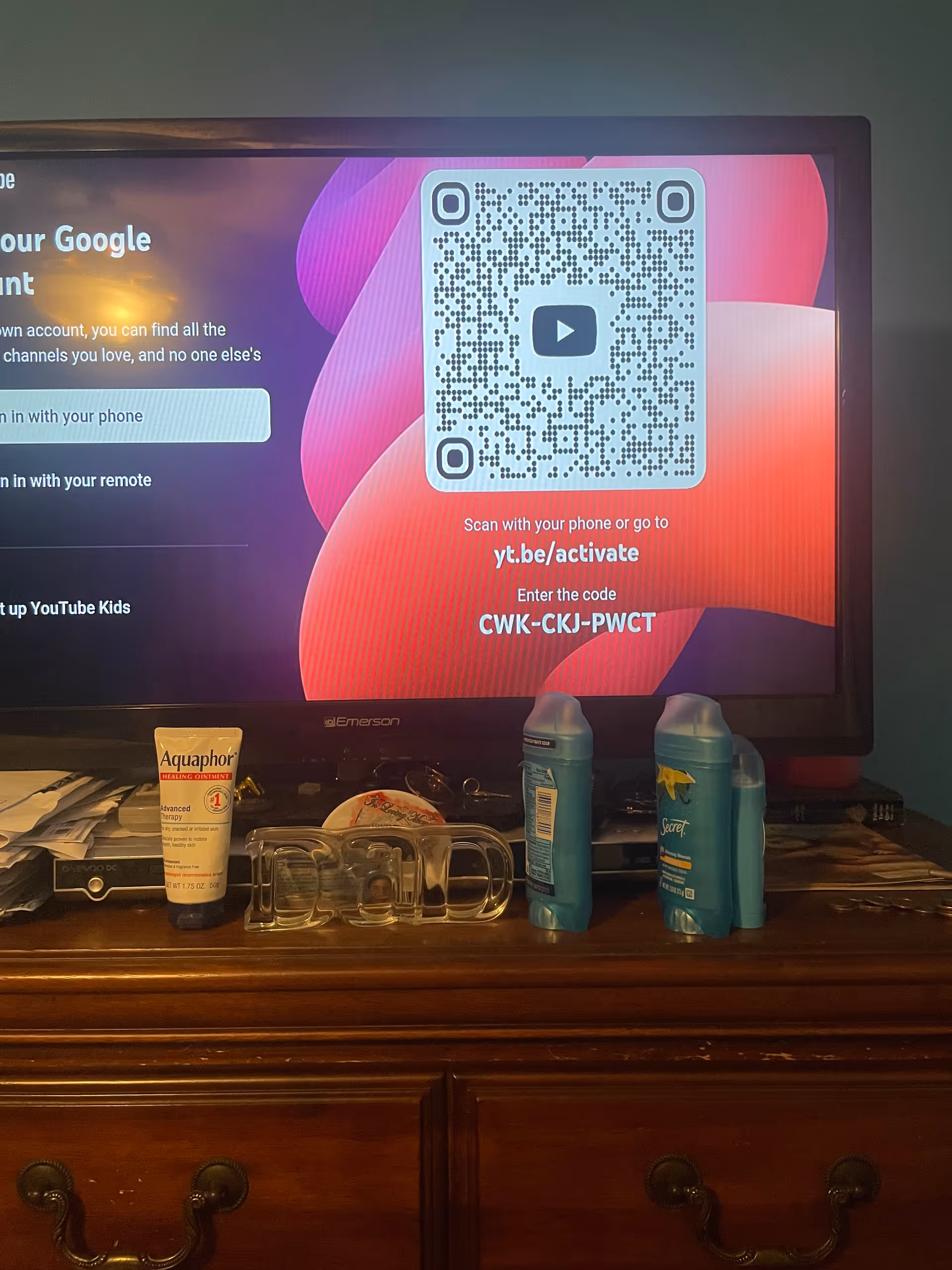 A TV screen shows a QR code while toiletries rest on a wooden dresser.