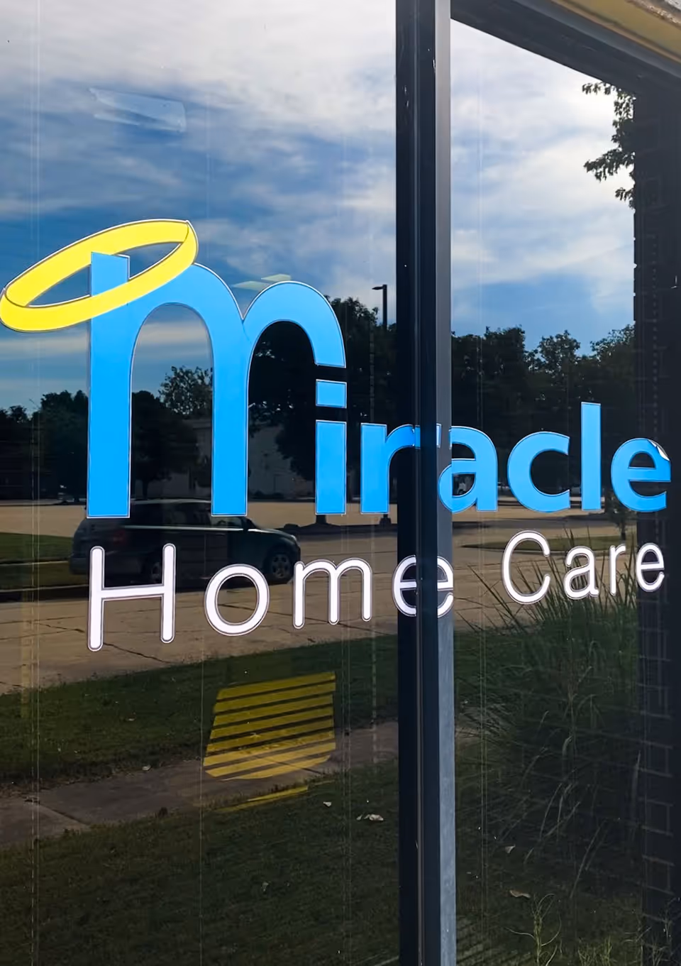 Glass storefront displays Miracle Home Care sign with blue logo and reflections.