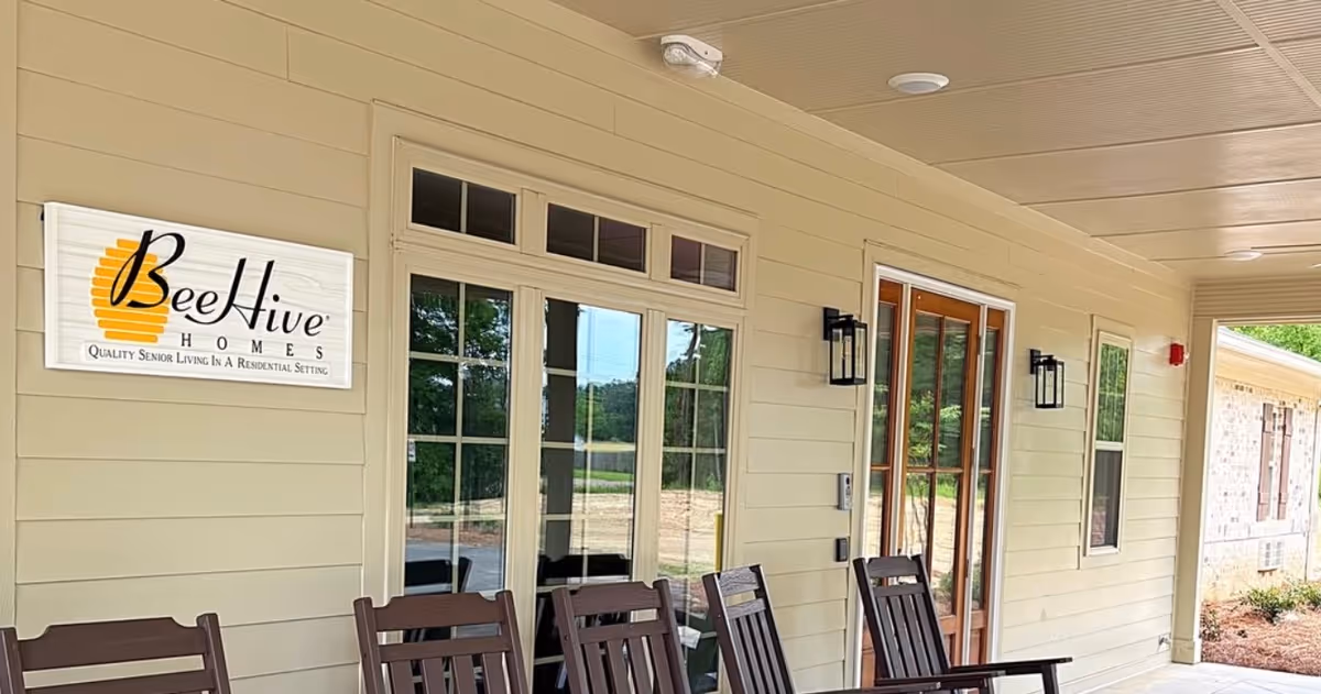 Exterior porch of BeeHive Homes of Batesville with chairs and a sign.