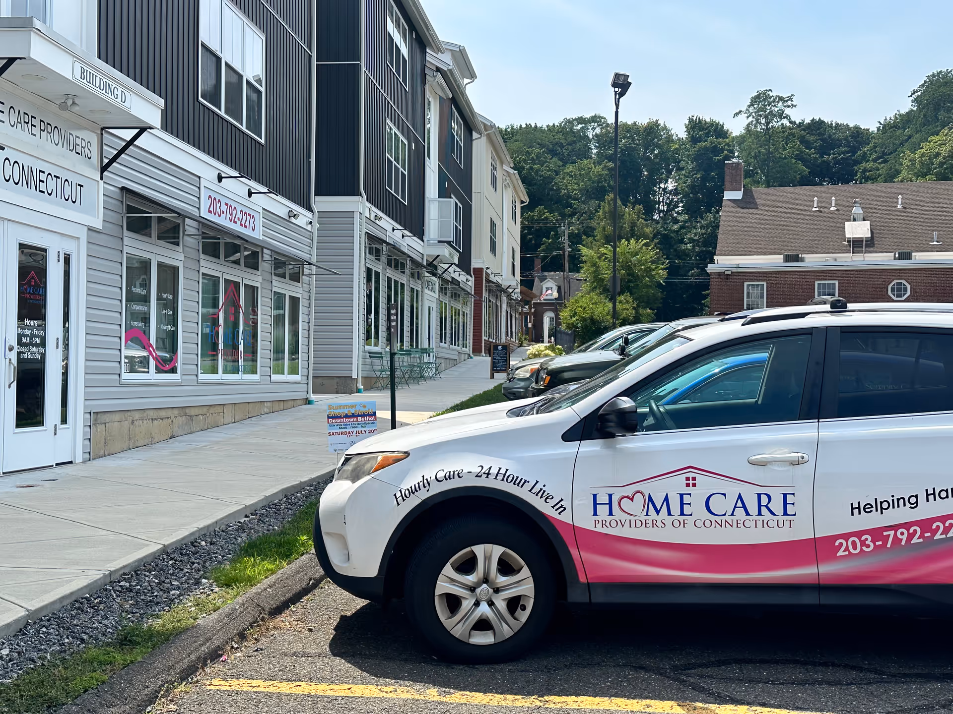 Exterior street view of storefronts with a Home Care Providers of Connecticut vehicle