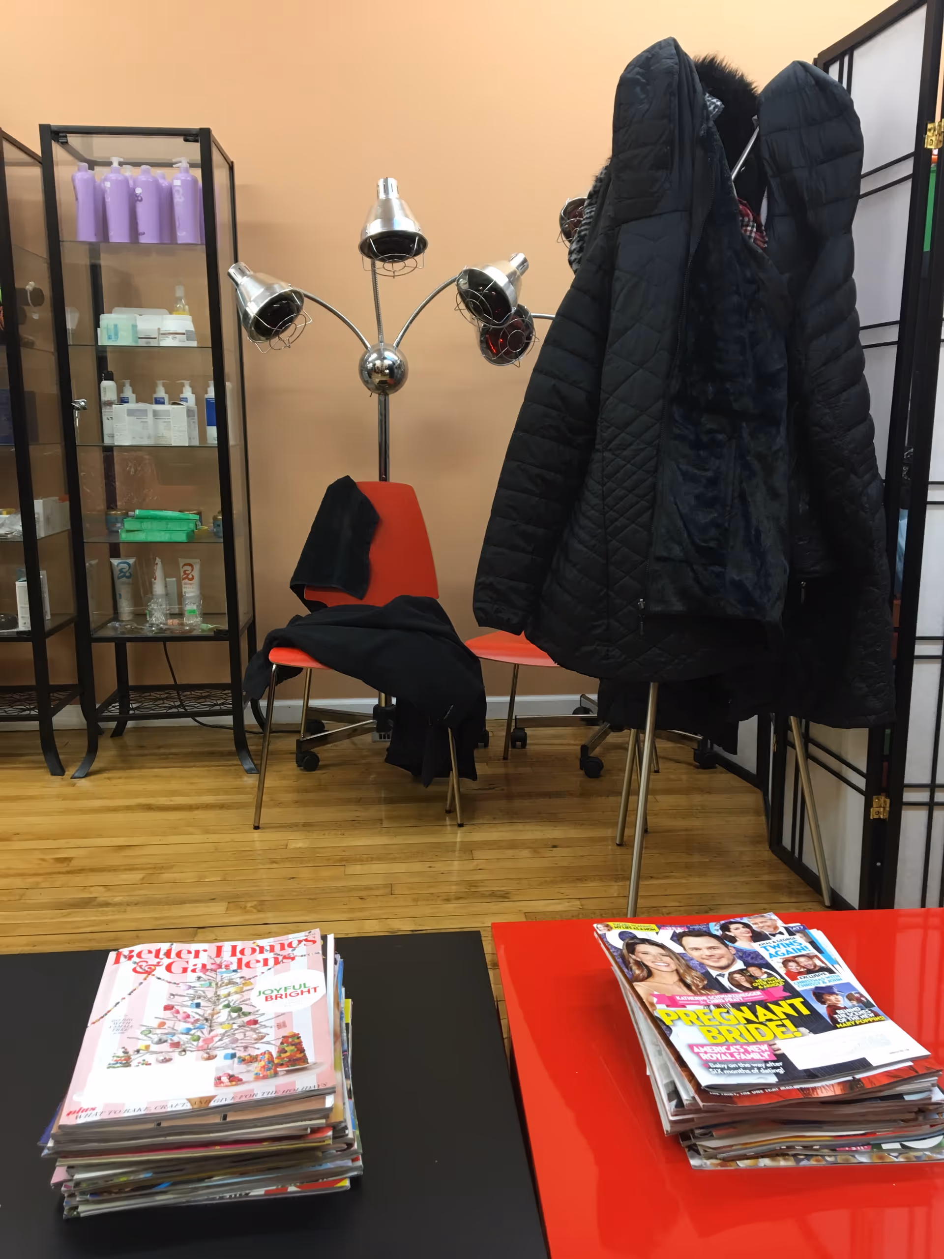 Small interior lounge with coat rack, jackets, and stacks of magazines on tables.