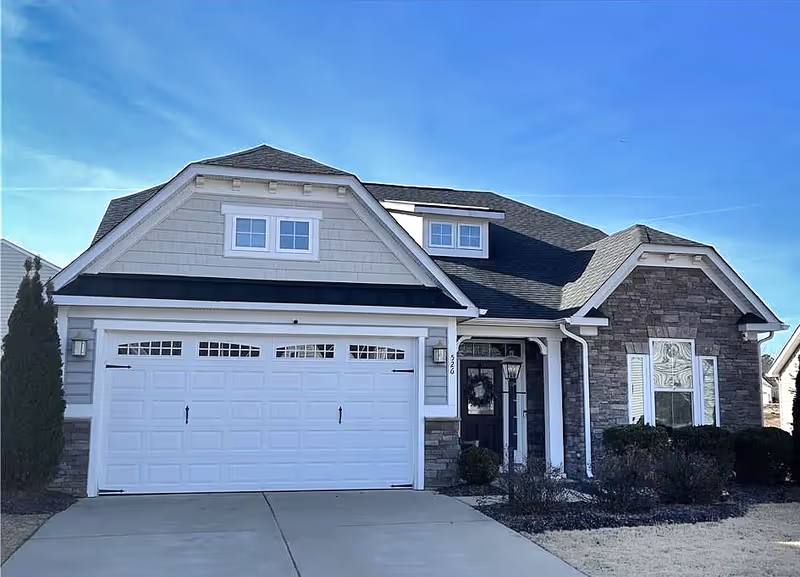 Front view of a suburban Elite Elder Care building with a two-car garage and stone exterior