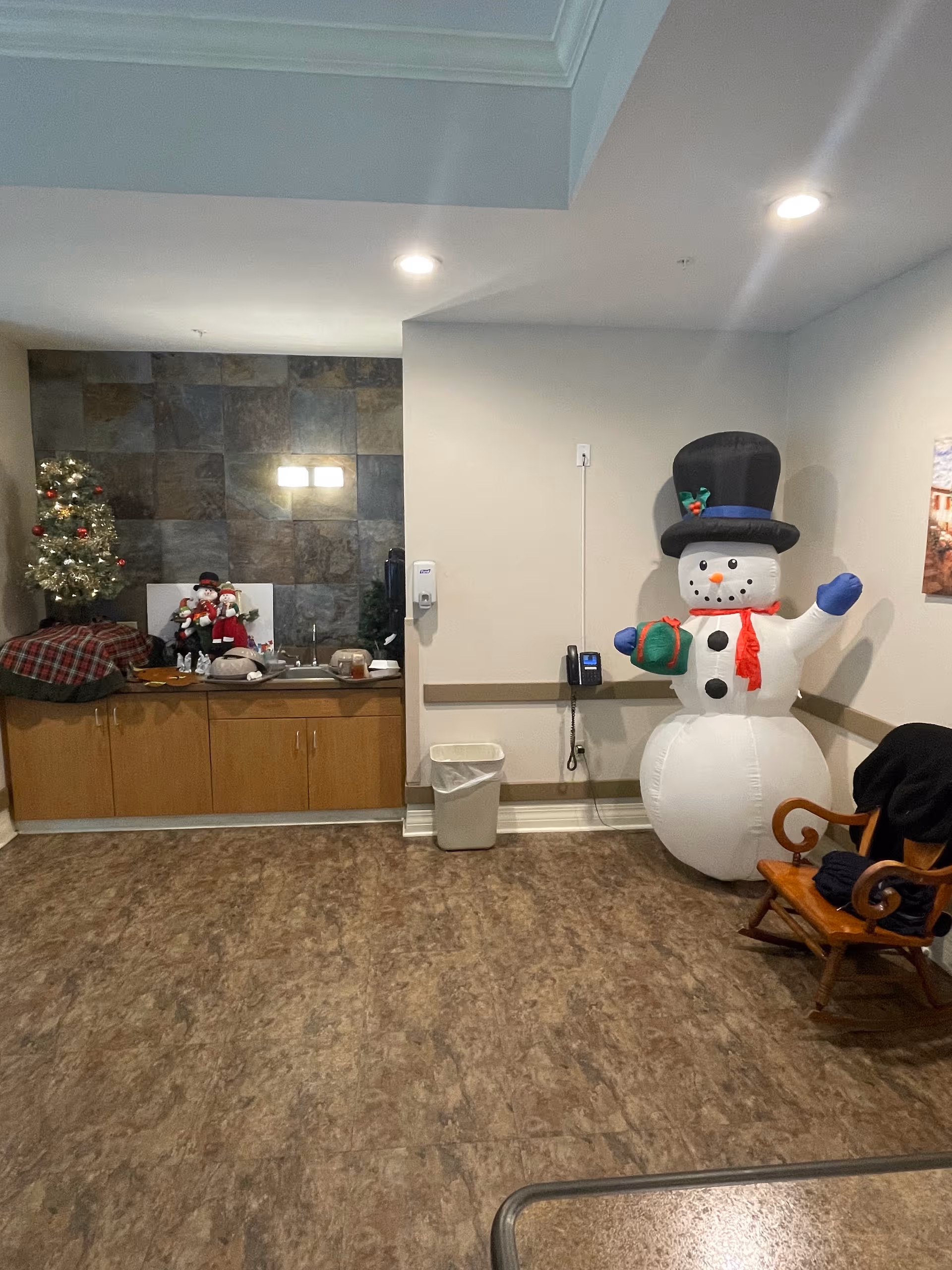 Indoor lobby with Christmas decor, a large inflatable snowman, and wooden cabinets.
