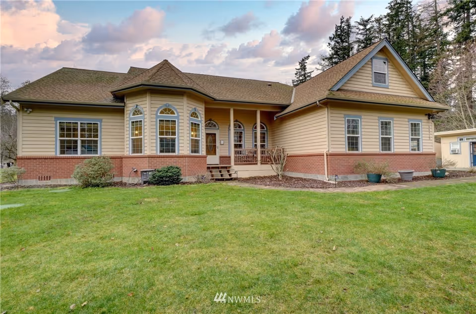 Beige, single-story home with a front porch, brick foundation, and green lawn.