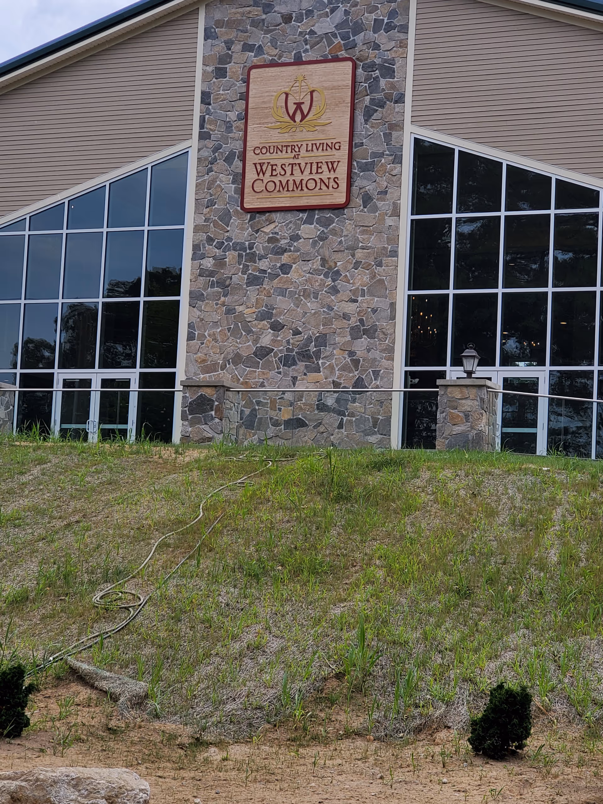 Front exterior of a stone-clad building with a Country Living at Westview Commons sign.