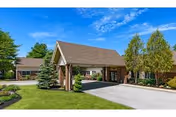 The Oaks senior living facility exterior with a covered entrance and manicured lawn.
