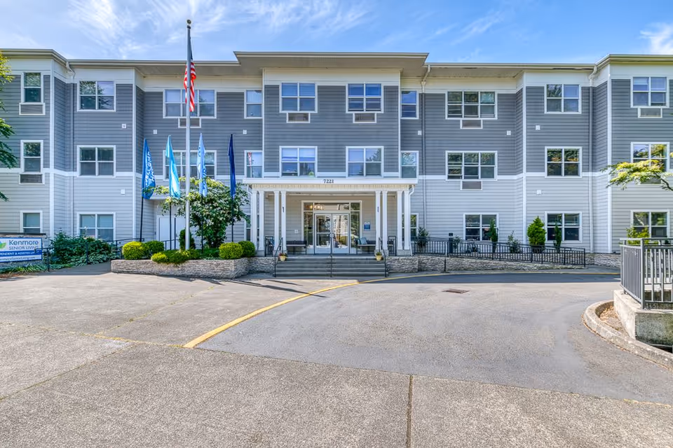 Front view of a multi-story senior living building with flags and entrance.