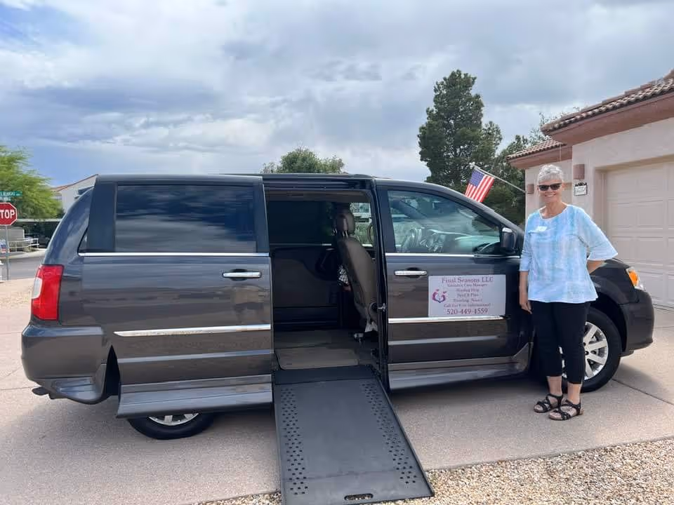 Dark accessible van with ramp parked outside a beige building; a woman stands beside it.