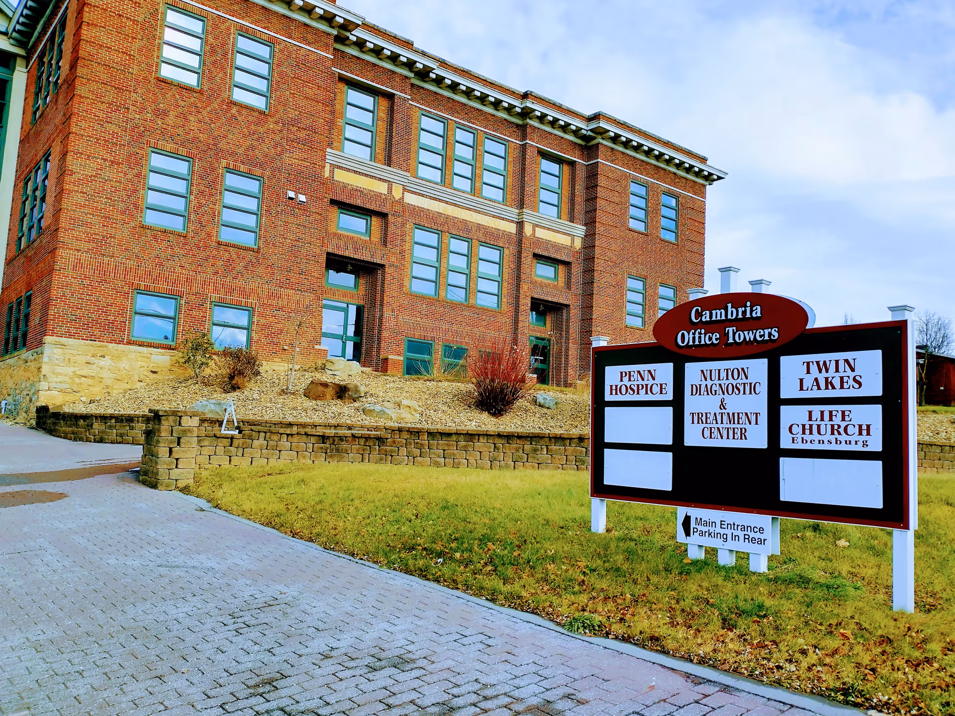 Brick building exterior with a multi-tenant signboard listing Penn Hospice and other offices.