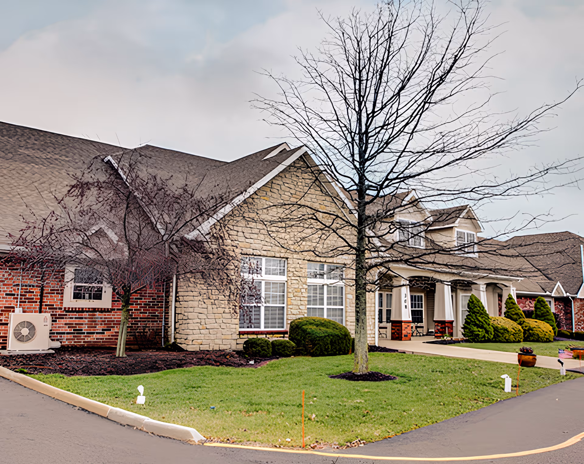 Front exterior of The Wyndmoor of Marion building with brick and stone facade, porch columns, leafless trees, and a driveway.