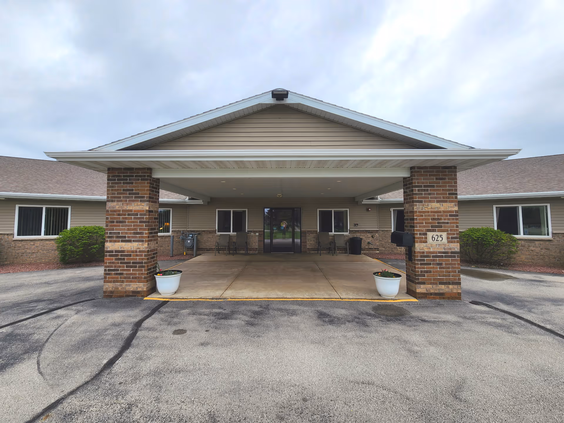 Covered front entrance of Rose Assisted Living Facility with brick pillars