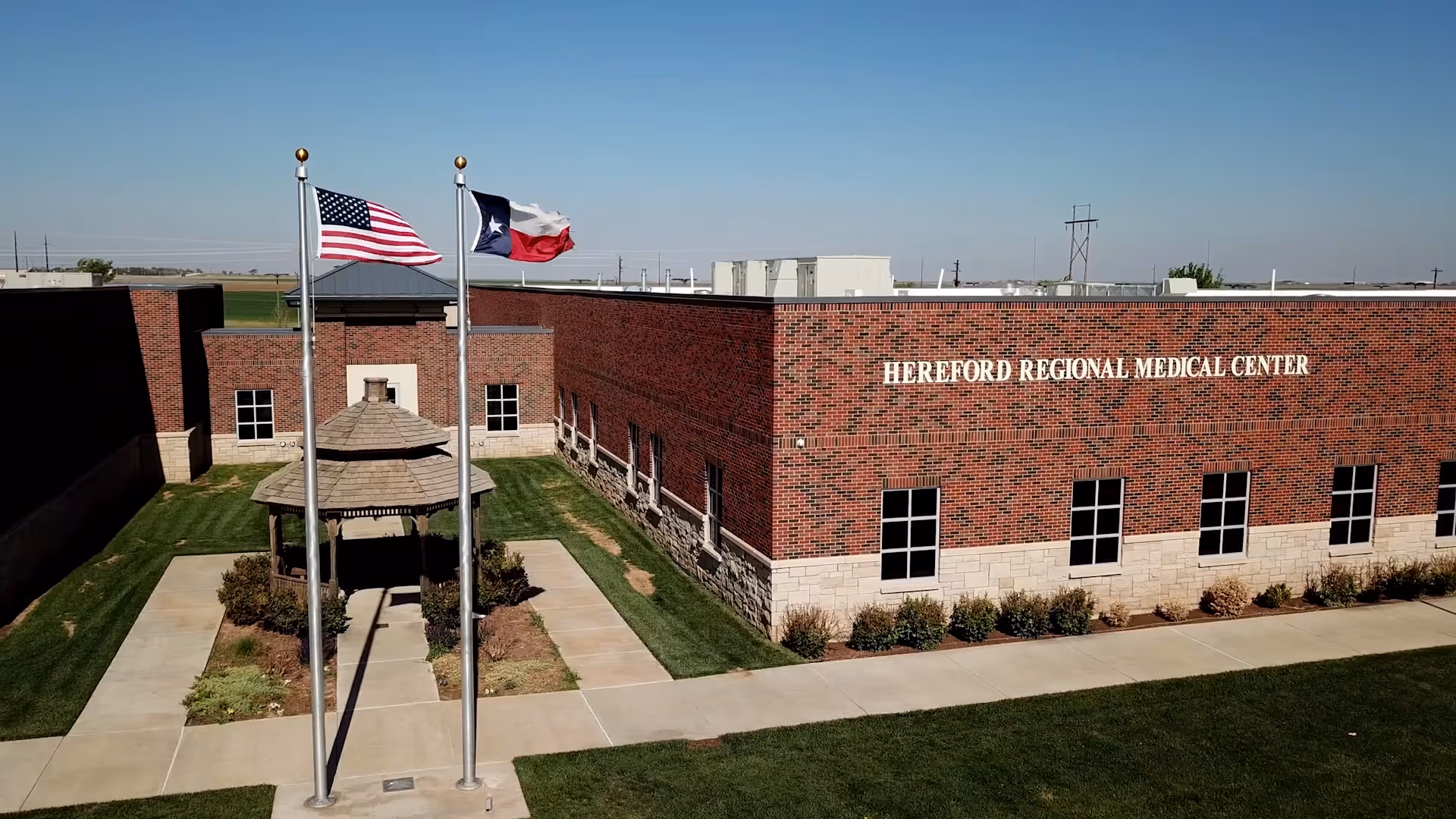 Exterior view of Hereford Regional Medical Center brick building with flagpoles and a gazebo.