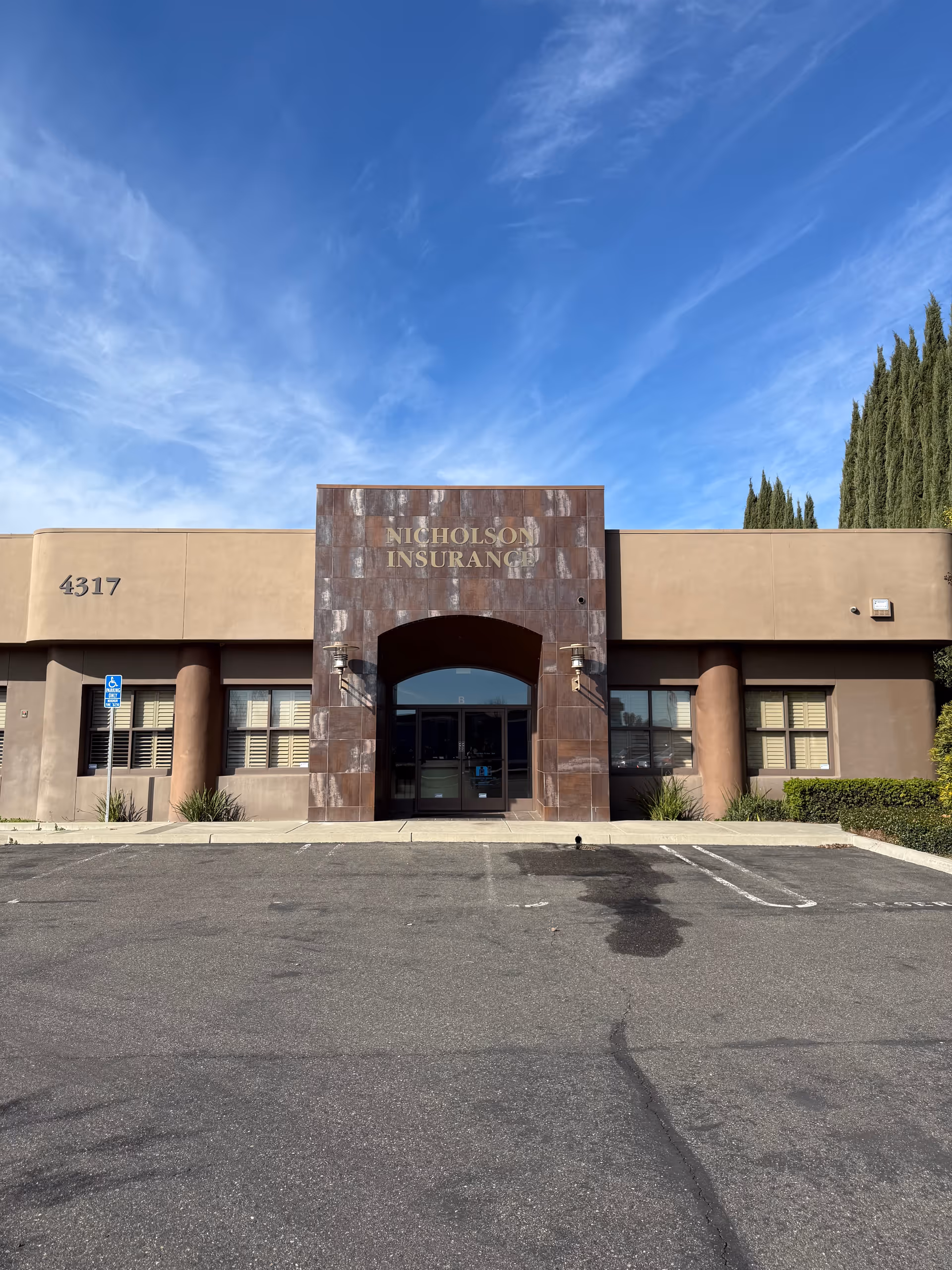 Front view of a single-story building entrance with a stone arch labeled Nicholson Insurance.