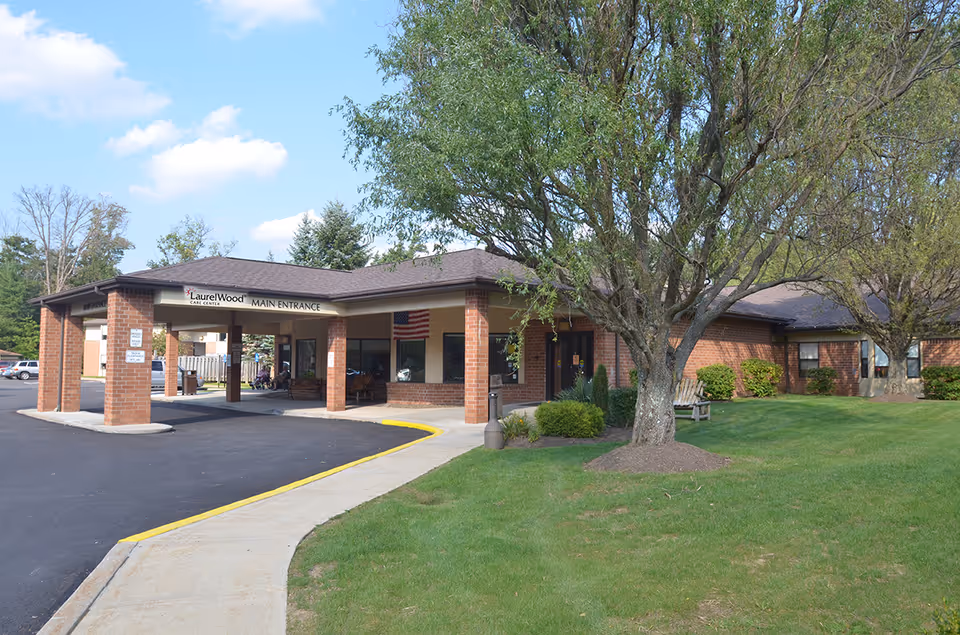 Amber Springs at Laurel Wood main entrance featuring brick building, pillars, and a landscaped lawn.