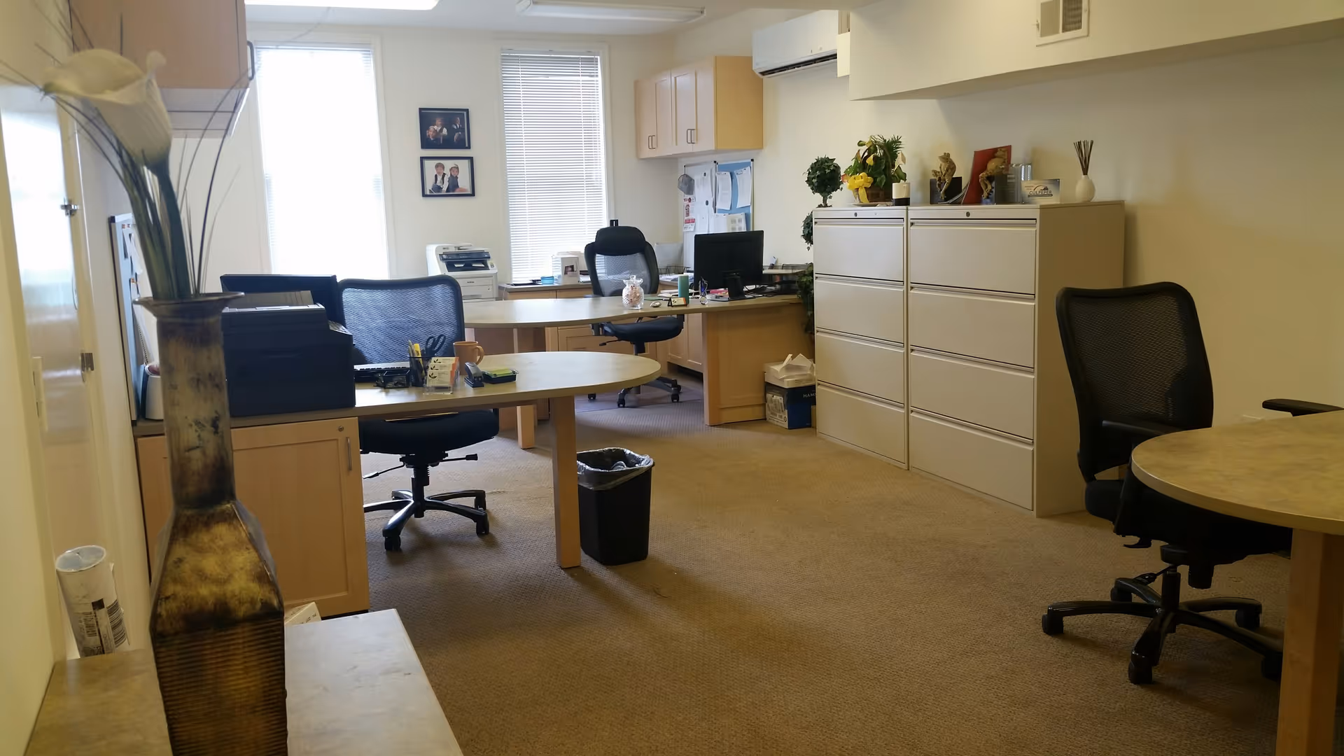 Office workspace inside a senior care facility with desks, chairs, computers, and filing cabinets.