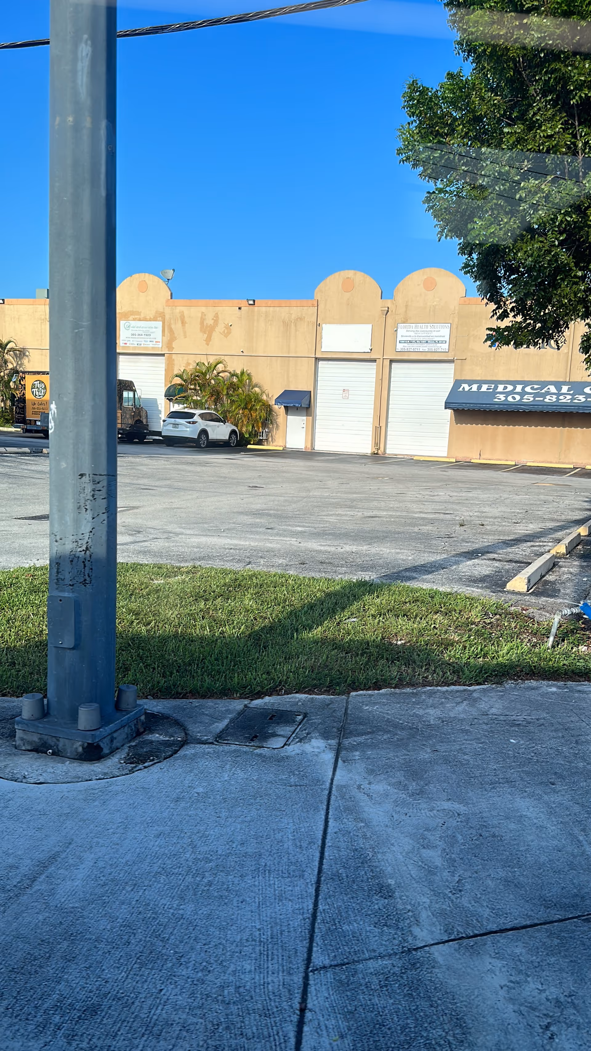 Exterior view of a beige medical building with parking lot and blue sky.