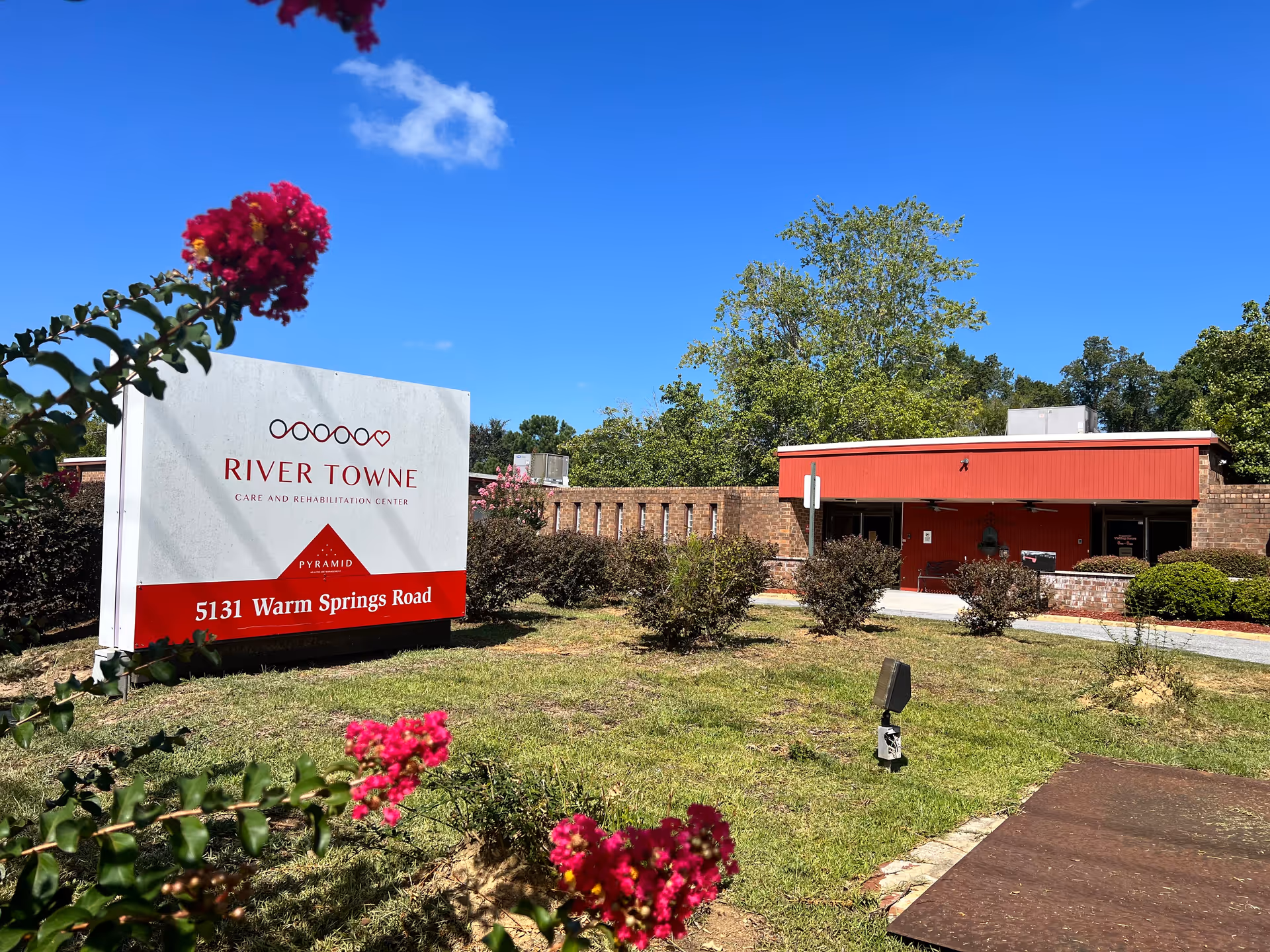 Exterior view of River Towne Center sign and red front building on a sunny day.