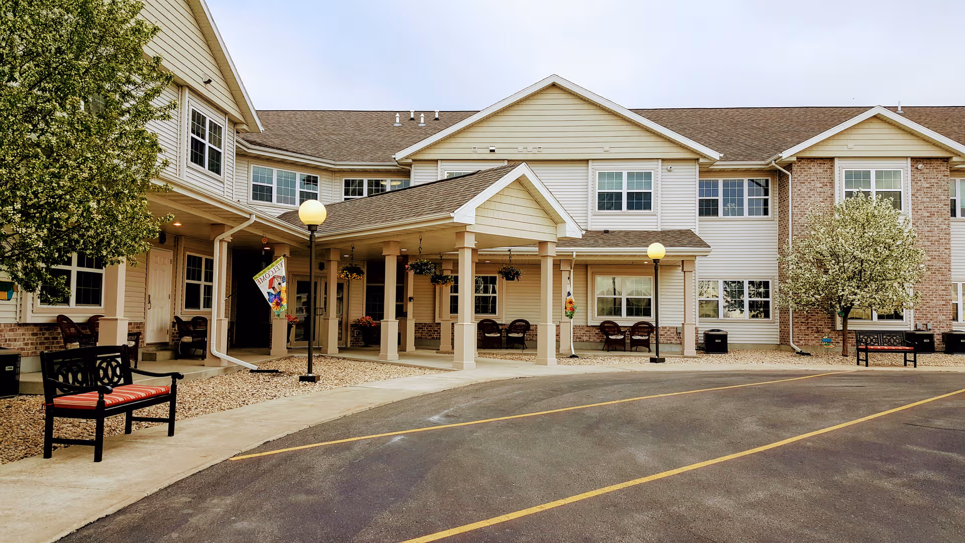 Exterior view of The Meadows of Fall River facility with entrances, pillars, and benches.