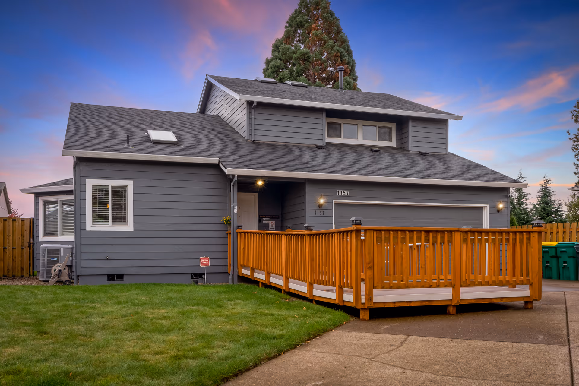 Gray two-story house exterior with a wooden ramp leading to the front entrance.