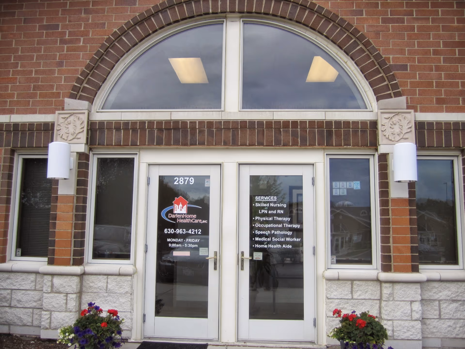 Exterior brick entrance of Darien Home Health Care with glass doors showing services.