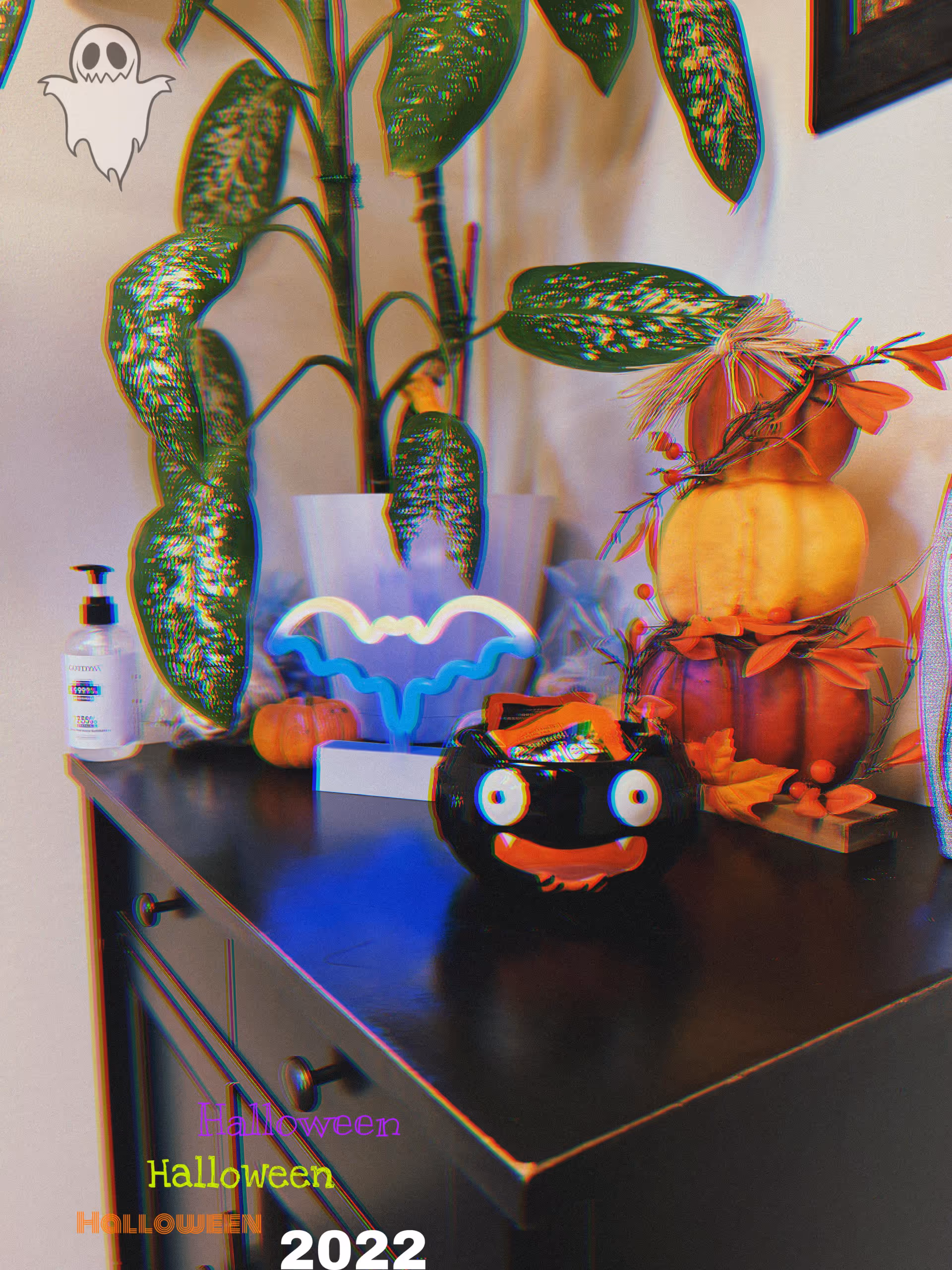 Indoor cabinet featuring a plant, pumpkins, Halloween candy bowl, and sanitizer bottle.