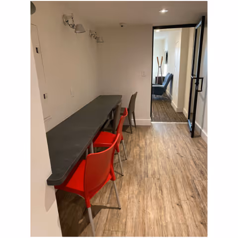 A narrow hallway features a long counter with red chairs along the wall.