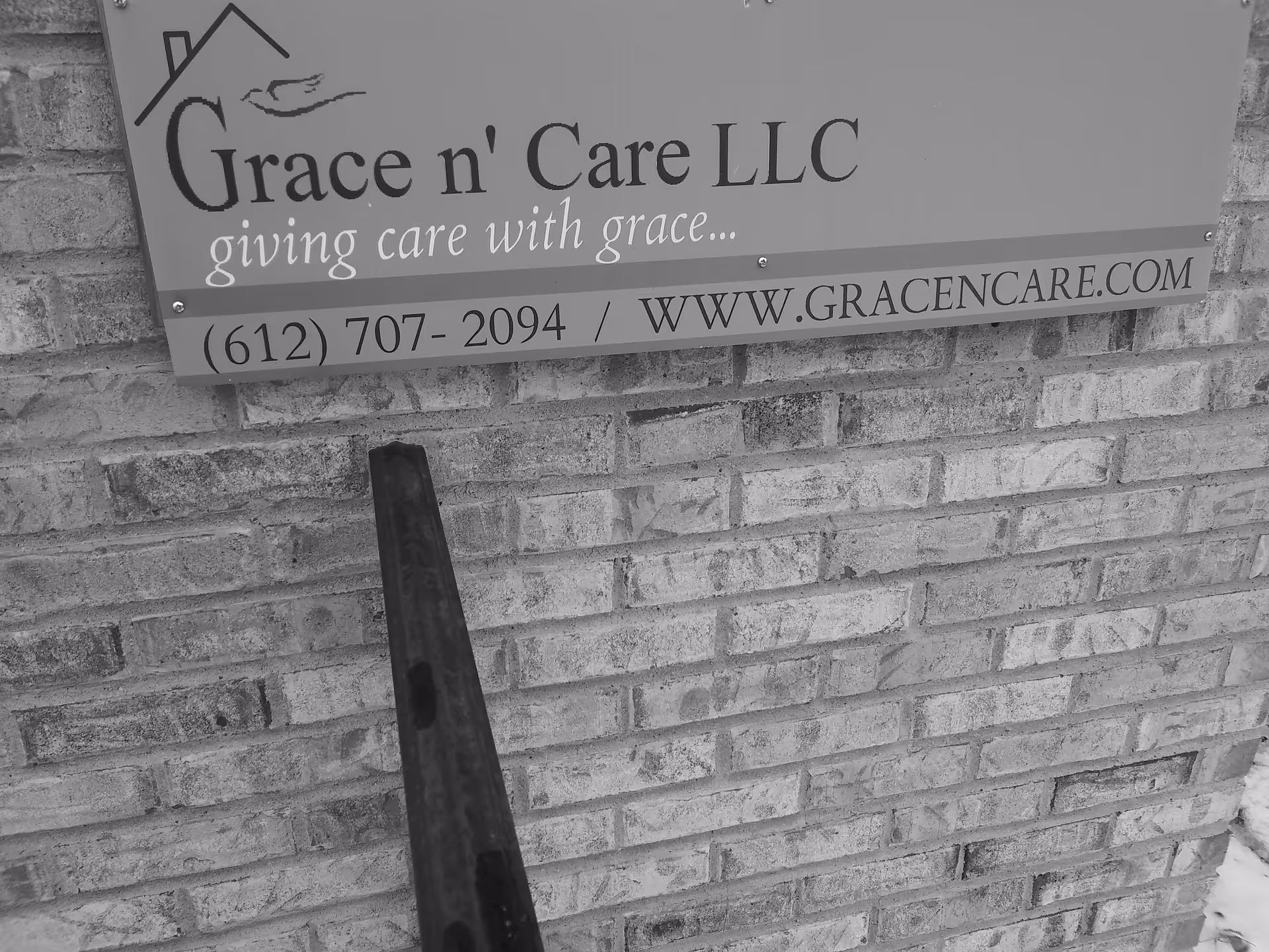 Exterior brick wall displays a Grace n' Care LLC sign with railing in foreground.