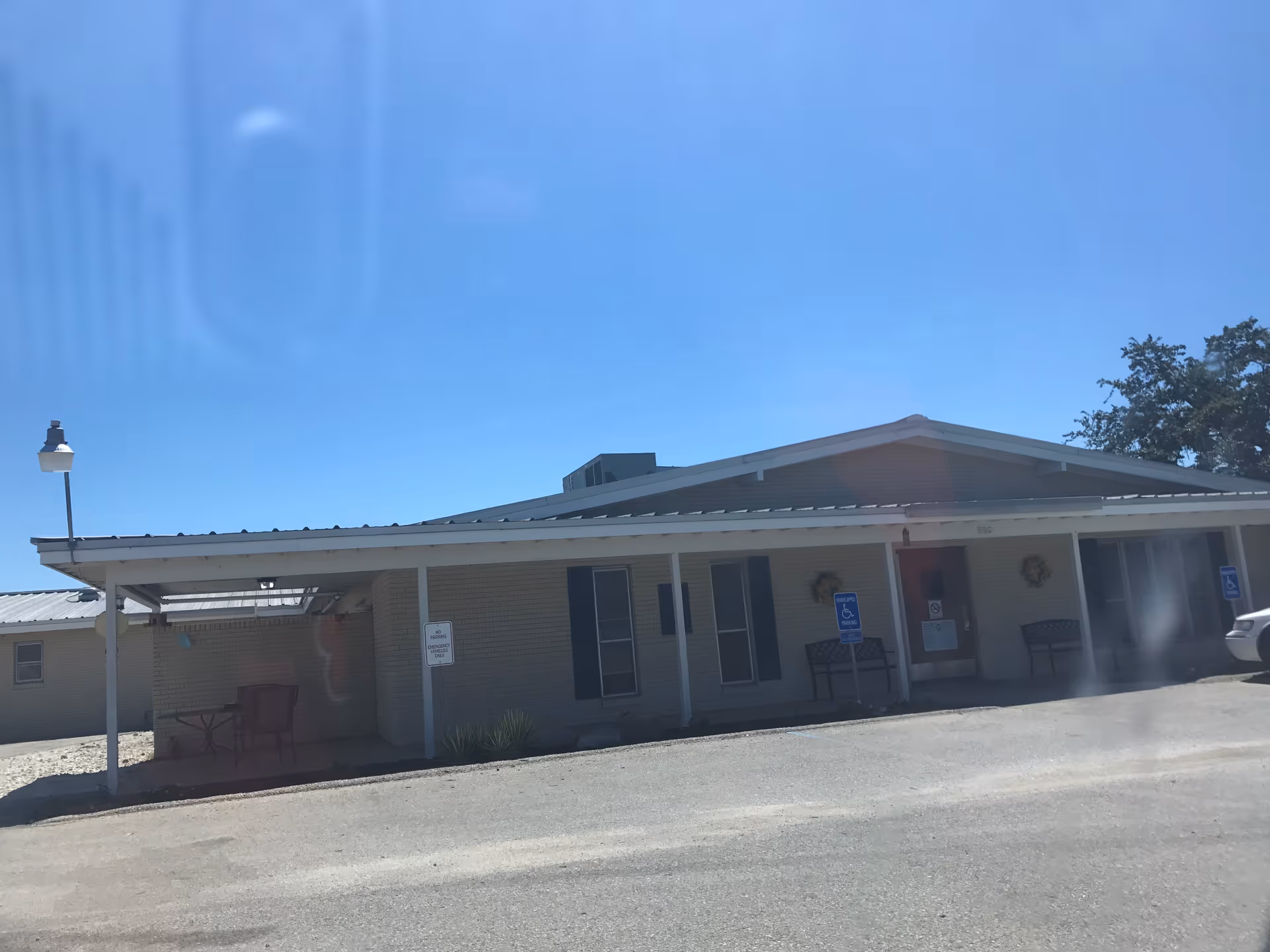 Front view of a single-story Will-O-Bell Assisted Living facility with entrance and handicap spaces.